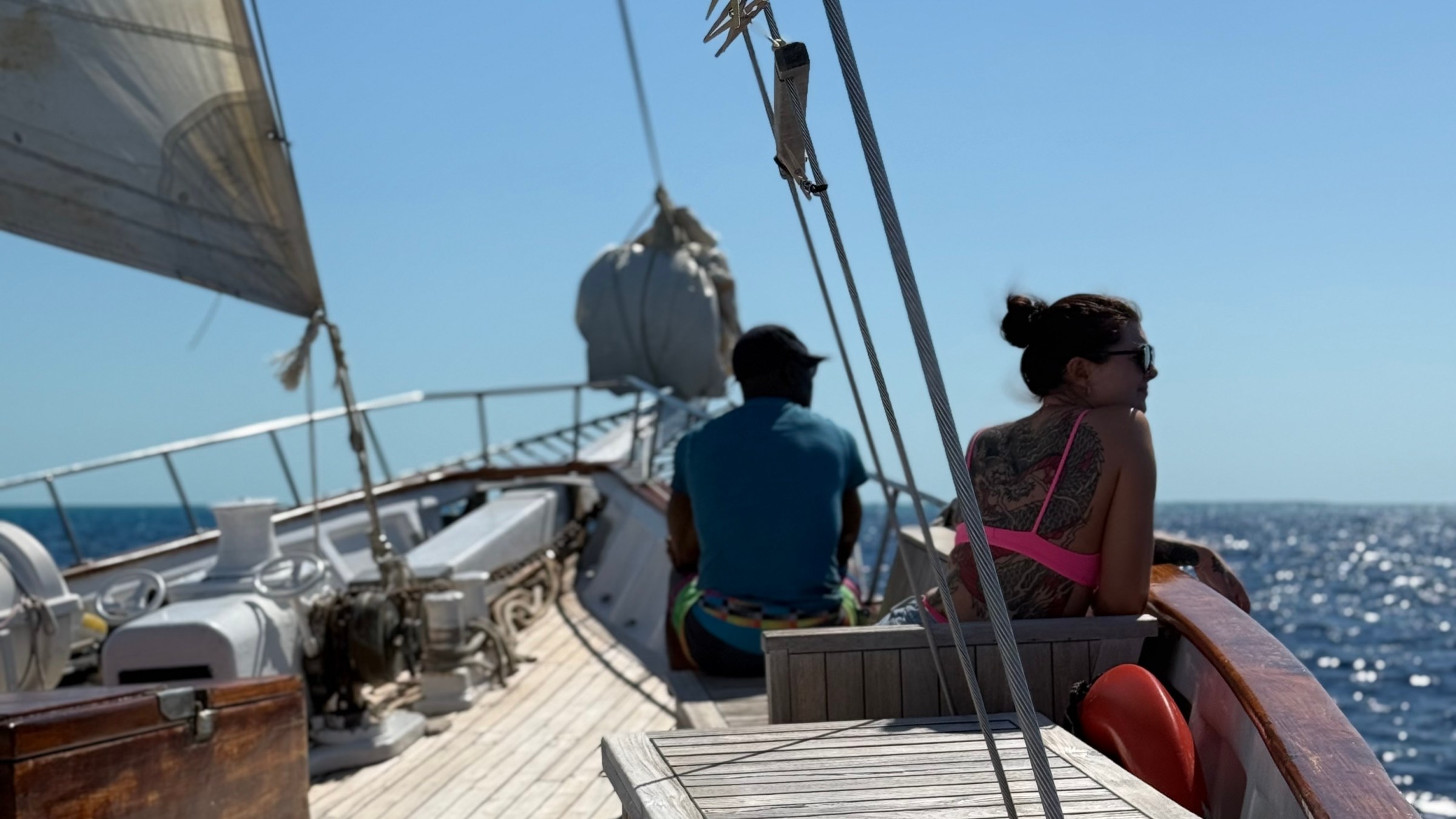 A woman sitting on the deck of the sailboat.