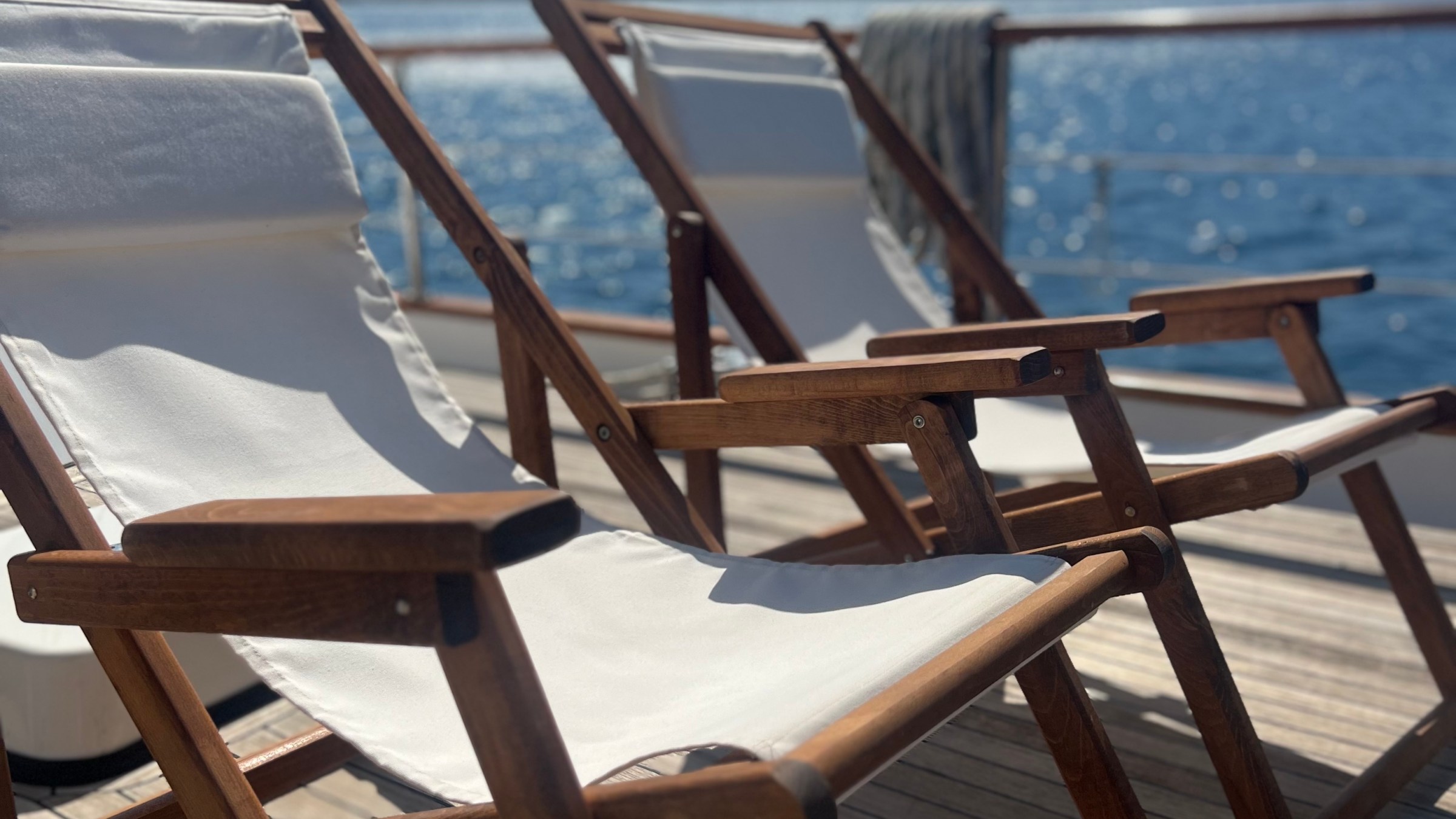 Two deck chairs on a wooden deck with a scenic ocean and mountain view.