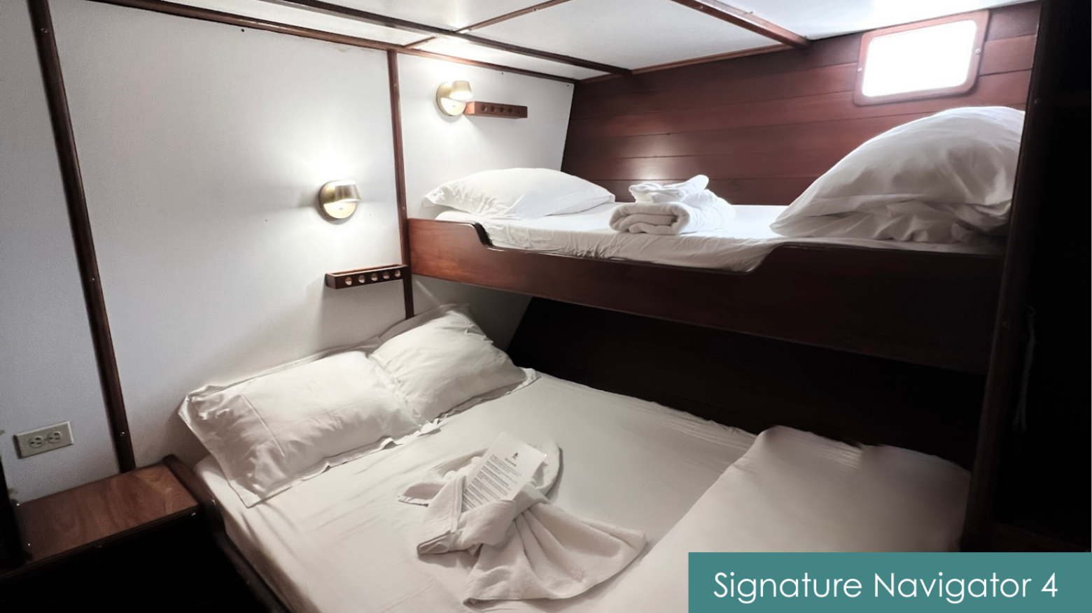 Small cabin with bunk beds, wooden walls, and a porthole window.