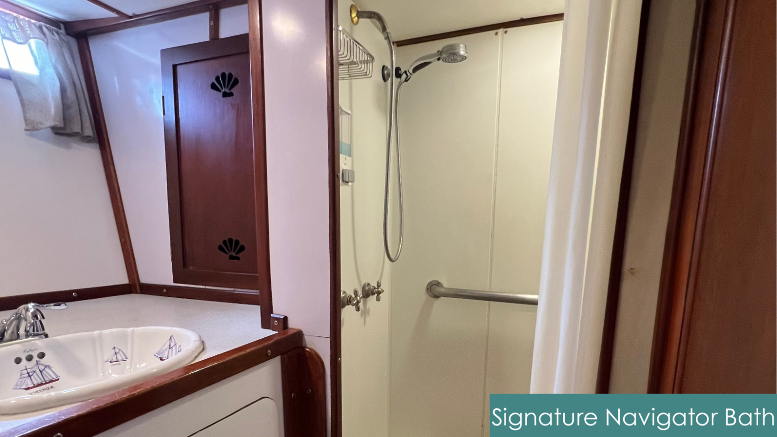 Small bathroom with a sink, mirror, shower, and wooden cabinet. Tiled countertop with nautical-themed designs.