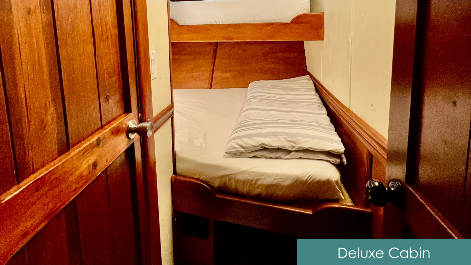 Wooden bunk bed in a cabin, with a neatly made lower bed and pillow.