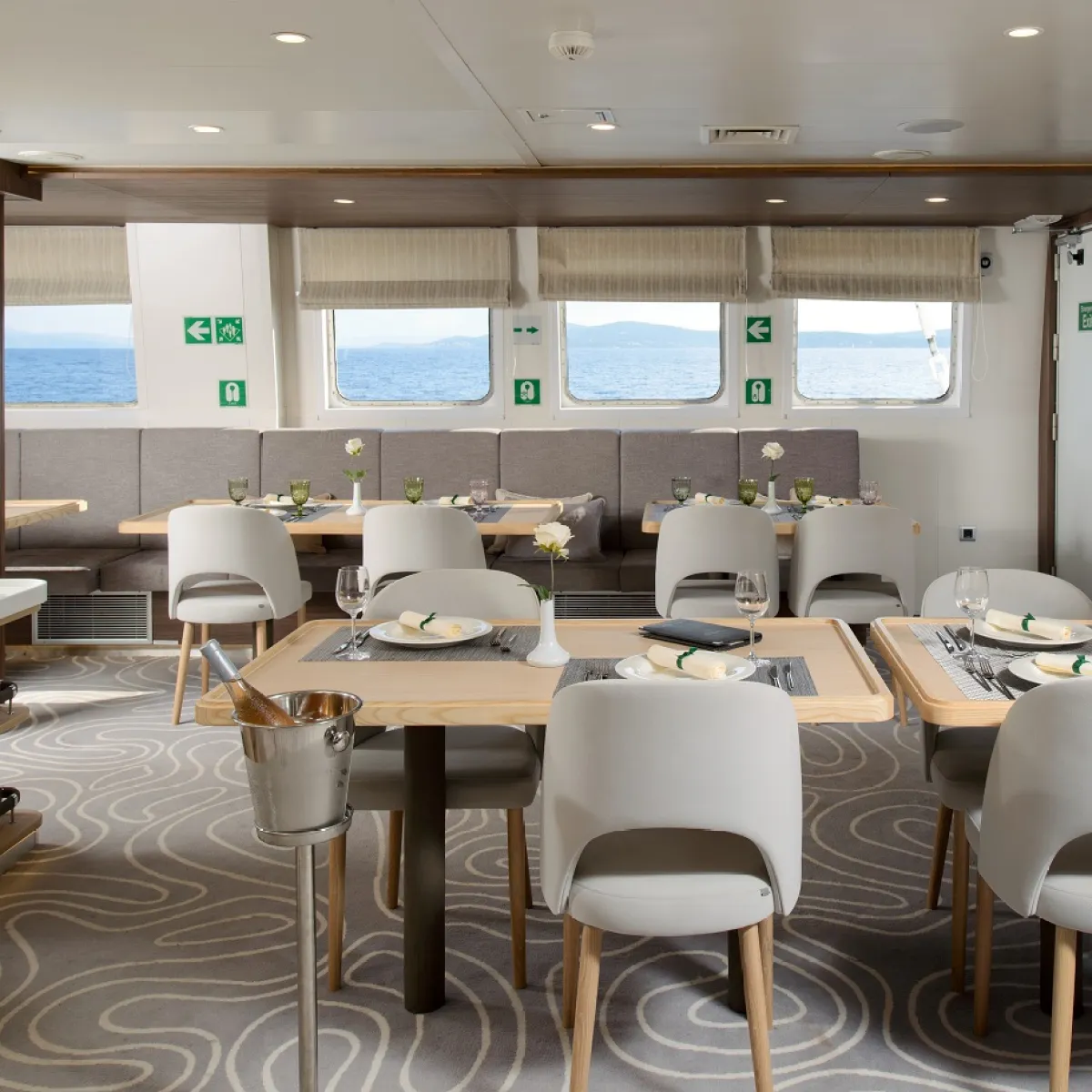 Elegant dining area on a ship with tables, white chairs, and ocean view.