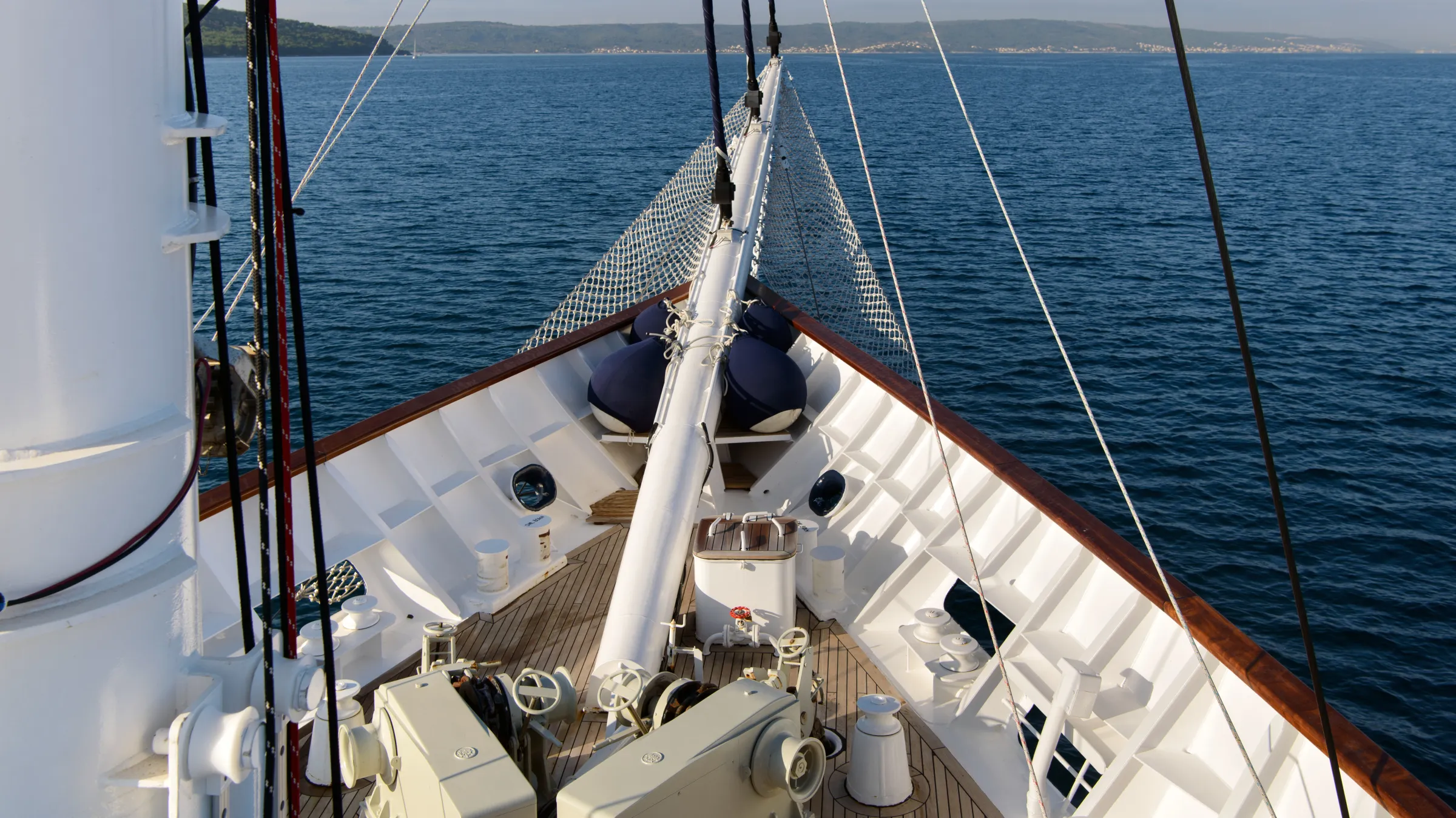 View from ship's bow with open sea and distant coastline.