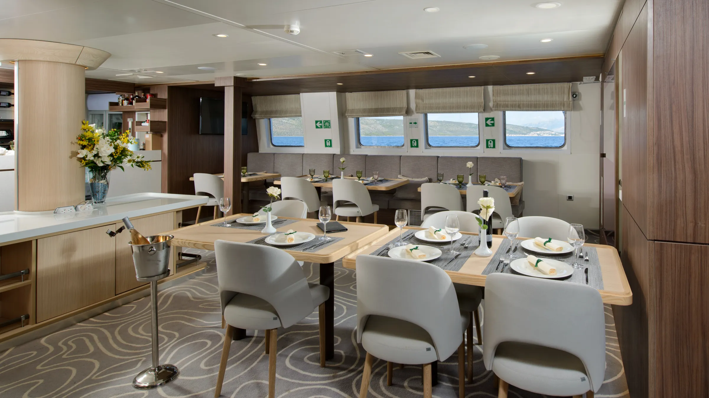 Elegant dining area on a yacht with set tables and window views.