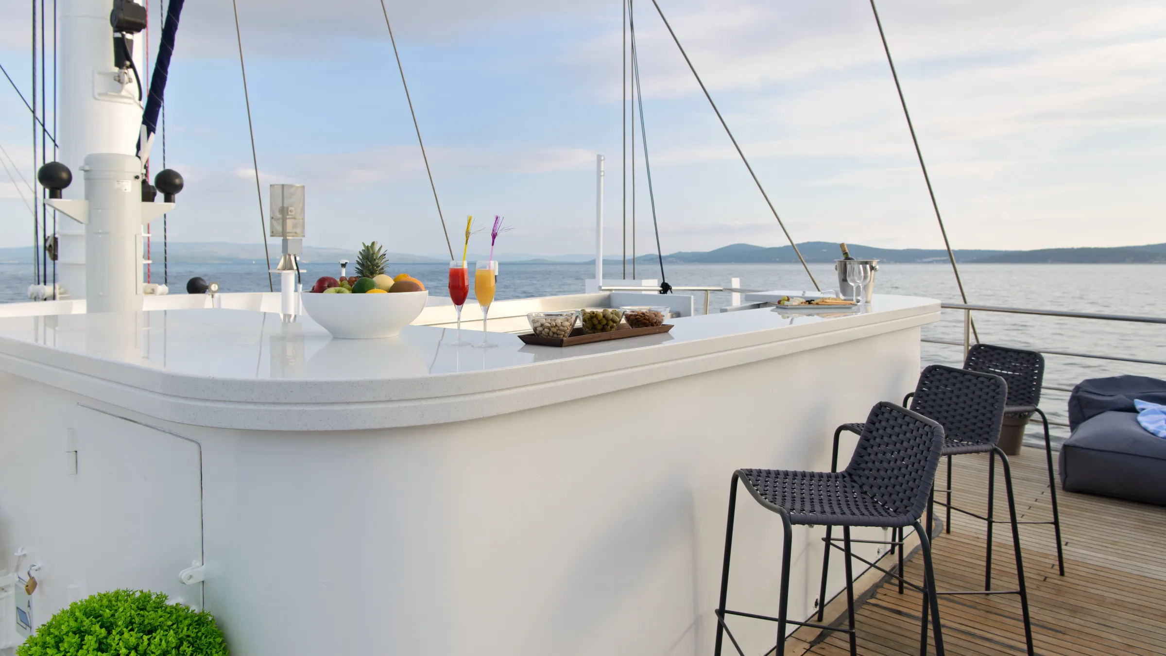 Yacht deck with outdoor bar, stools, and sea view.