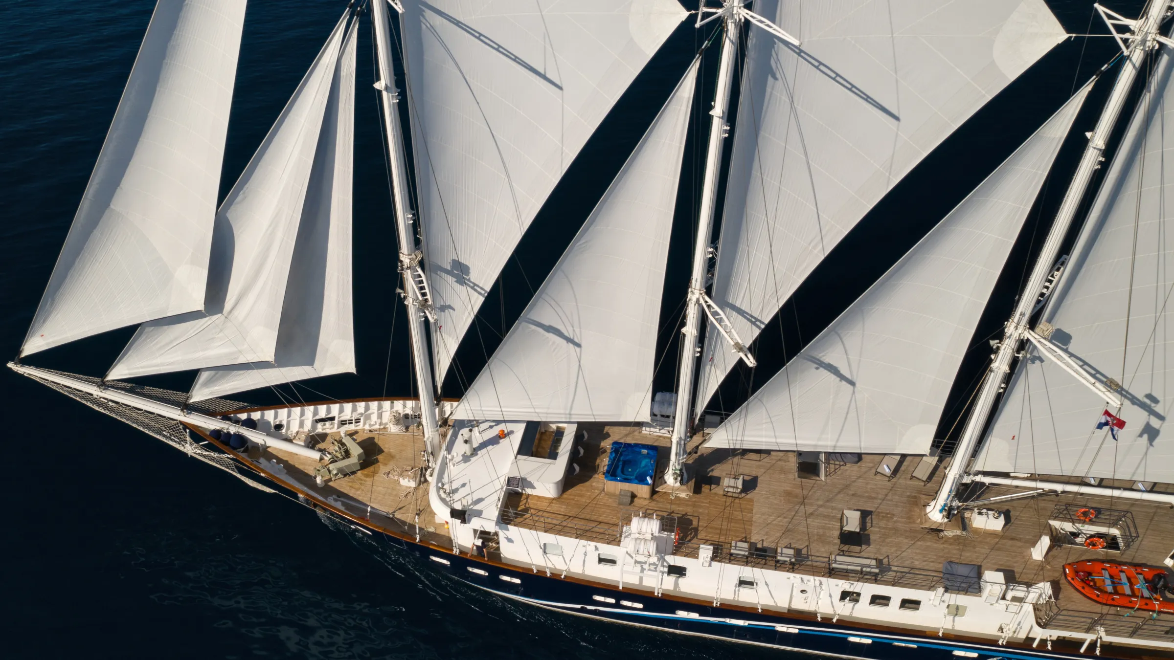 Aerial view of a large sailing ship with white sails on the water.