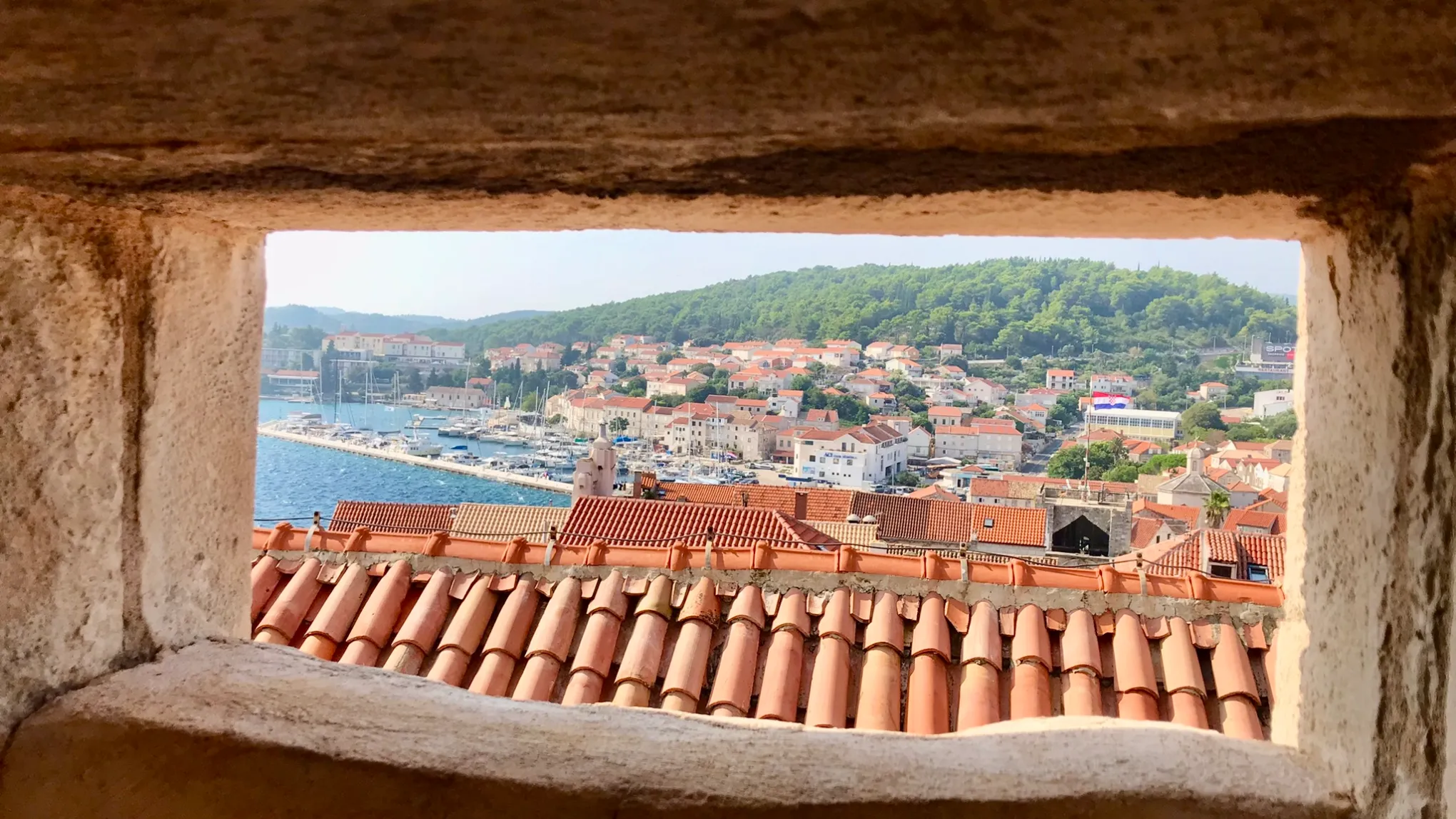View of coastal town and harbor through a stone window.